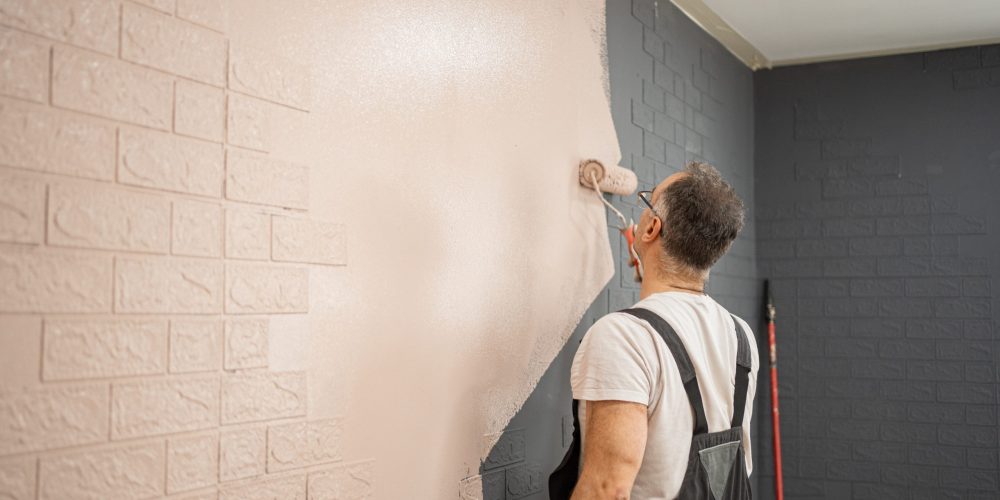 Man Painting Brick Wall With Paint Roller